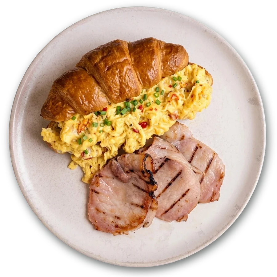 Chilli scrambled eggs on a croissant with grilled bacon, from above