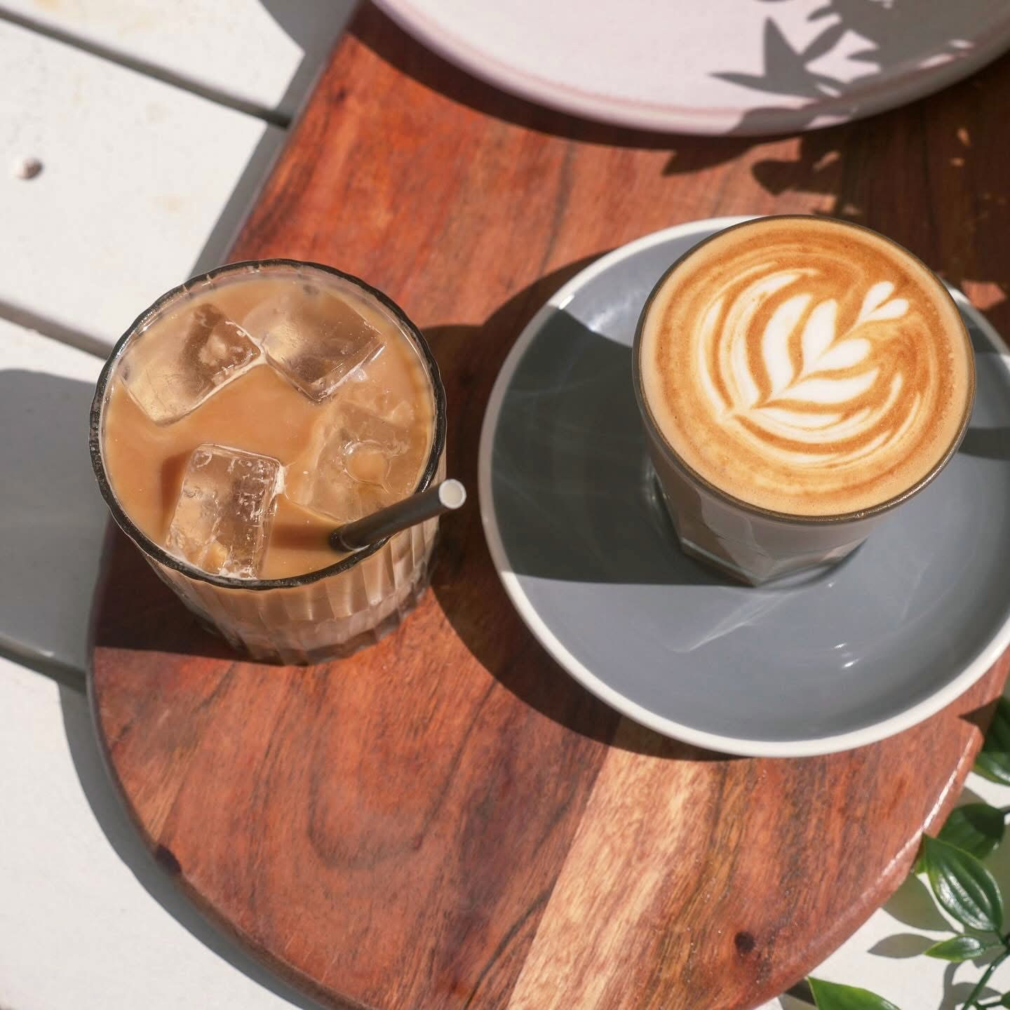 An iced latte and a flat white on a timber board at Oar, from above