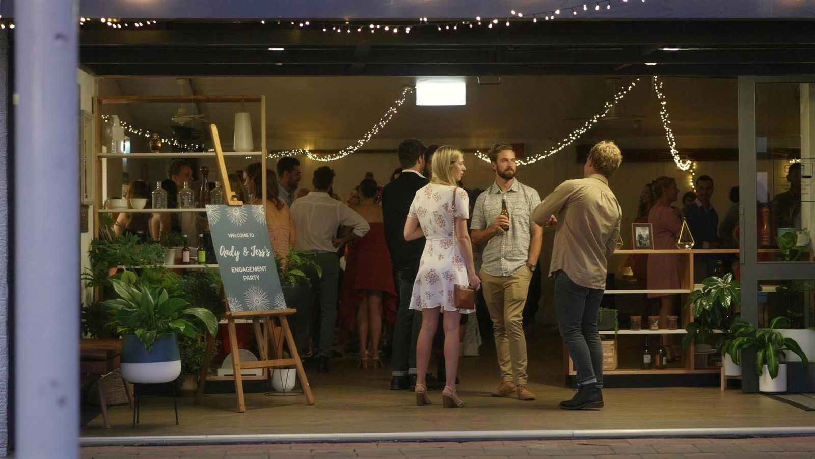 Guests under strings of fairy lights at an evening celebration at Oar, beside the lake