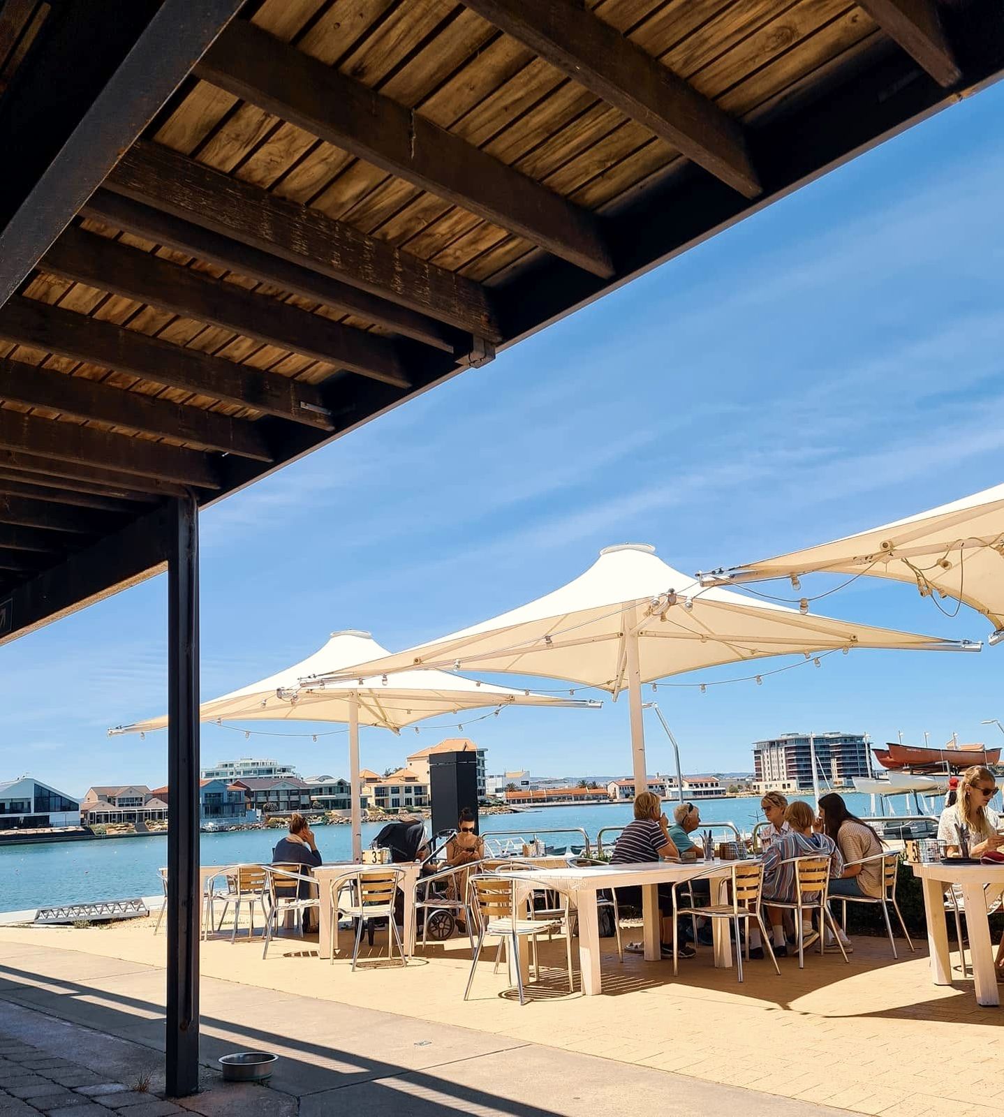 Brunch tables under the white sails on the deck at Oar, looking out to the lake