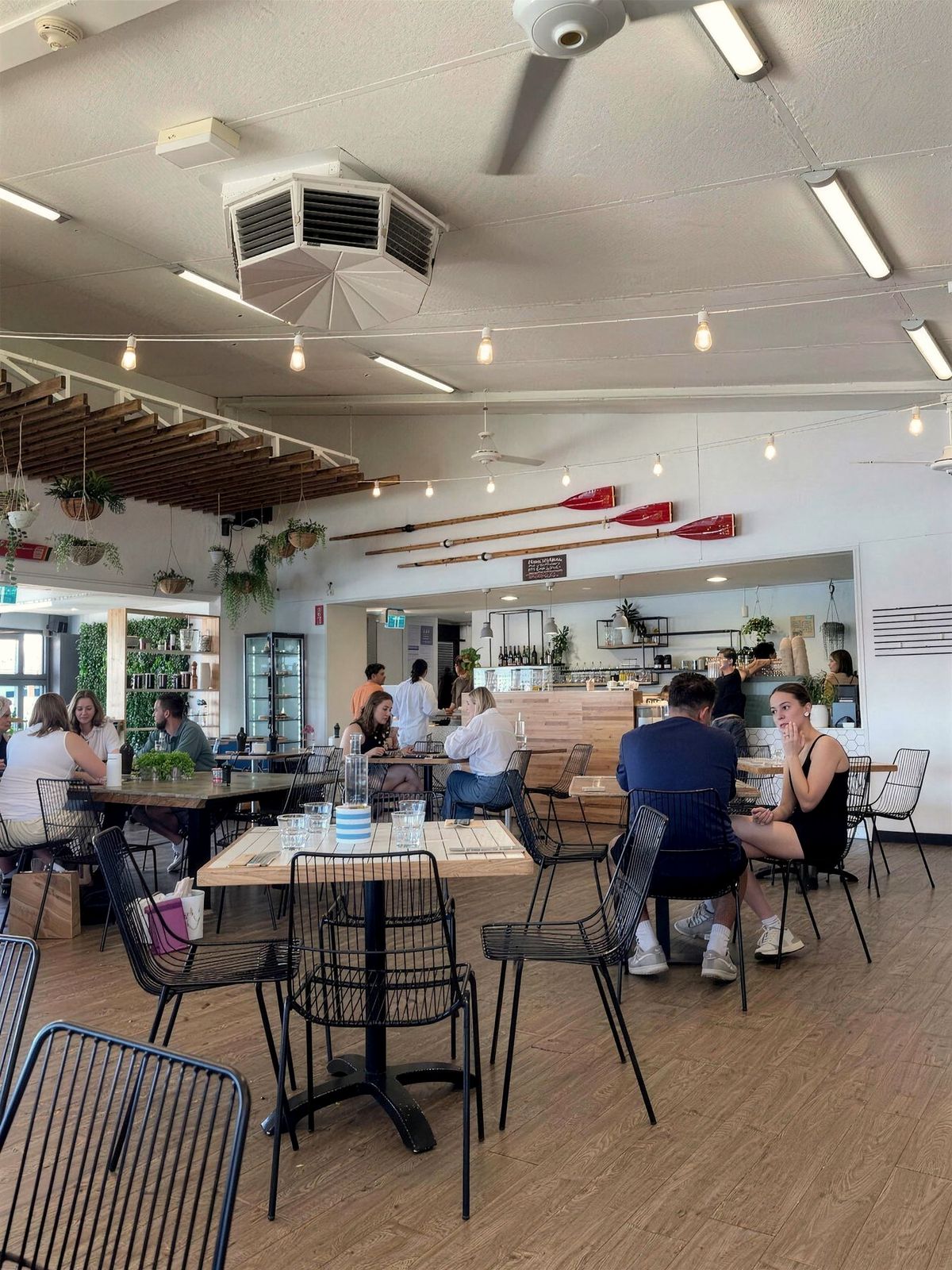 Inside Oar at lunchtime, with oars on the wall, timber tables and festoon lights