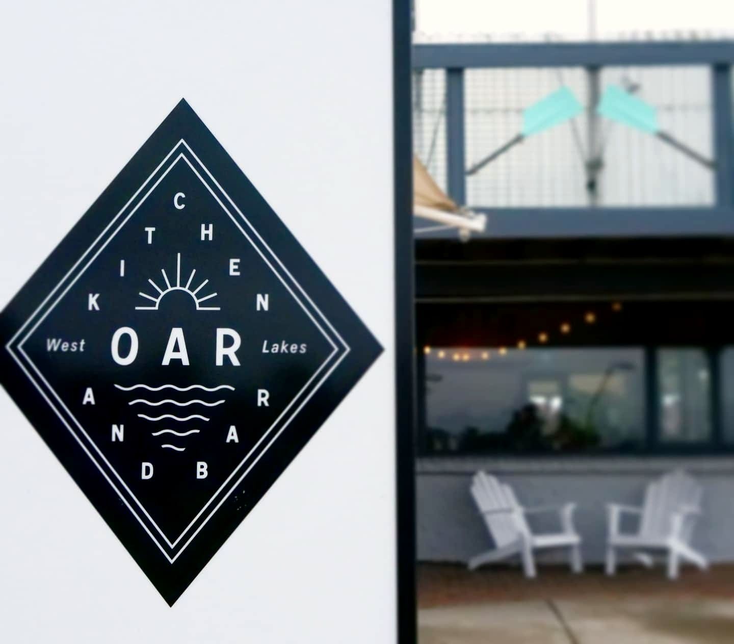 The Oar Kitchen and Bar sign at the entrance, with the deck and chairs behind