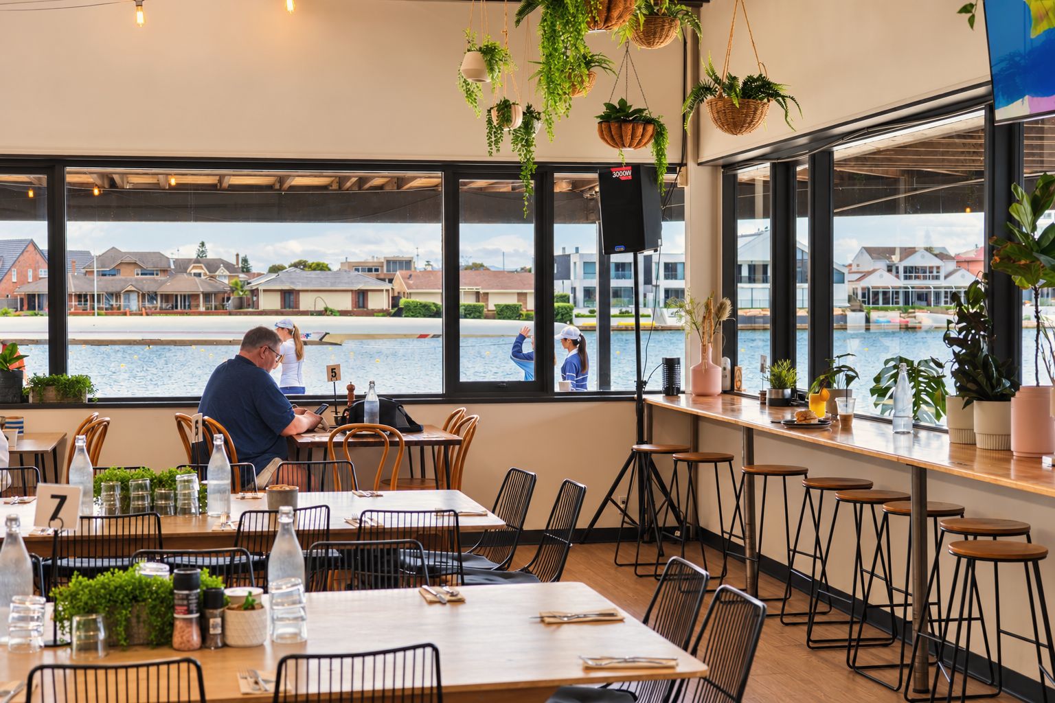 Inside Oar, timber tables and stools along wide windows that look straight out over the lake, with rowers on the jetty